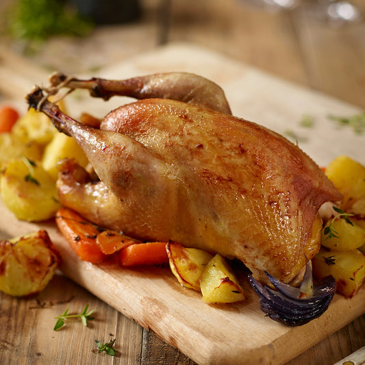 Roasted pheasant with vegetables on a wooden cutting board