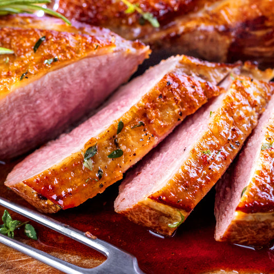 Sliced roasted meat with a fork on a wooden cutting board