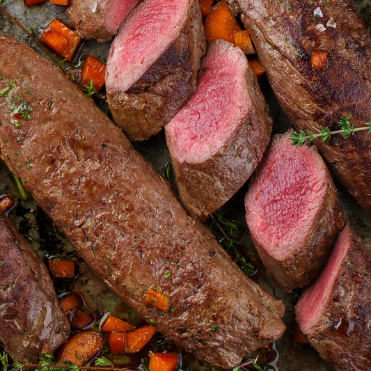 Sliced venison striploin with vegetables on a pan