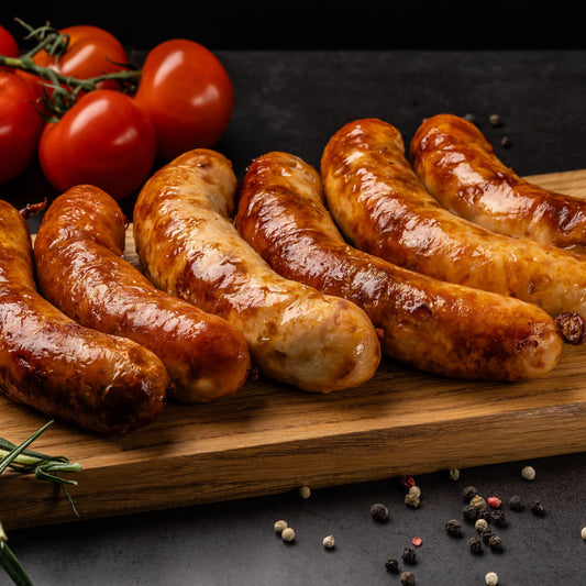 Grilled wild boar chilli sausages on a wooden board with cherry tomatoes and spices.