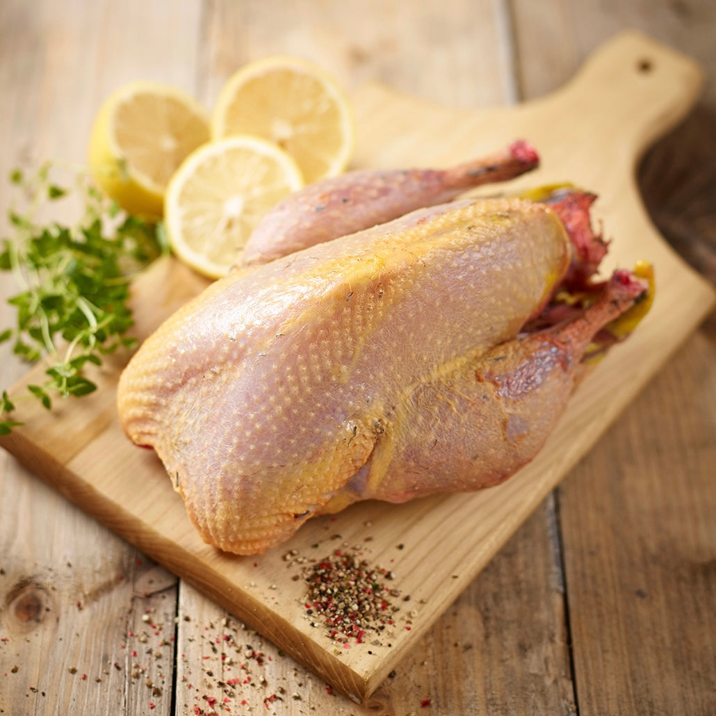 Raw game meat on a wooden cutting board with lemons and herbs